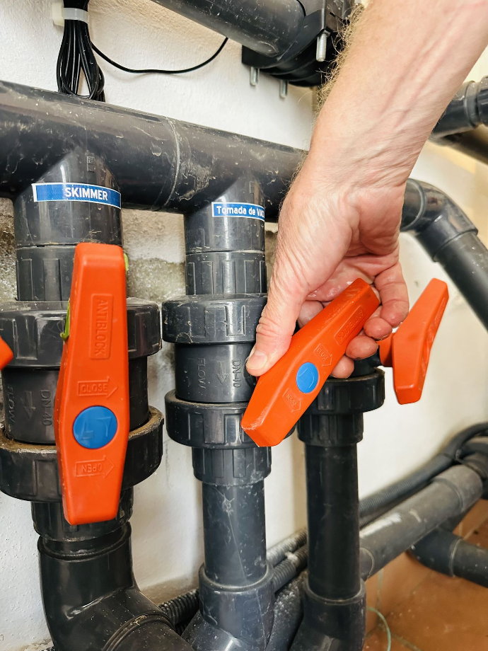 Technicien manipulant une vanne piscine dans un local technique des Bouches-du-Rhône