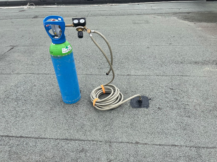 Technicien utilisant du traceur gaz pour détecter une fuite sur une toiture terrasse dans les Alpes De Hautes Provence
